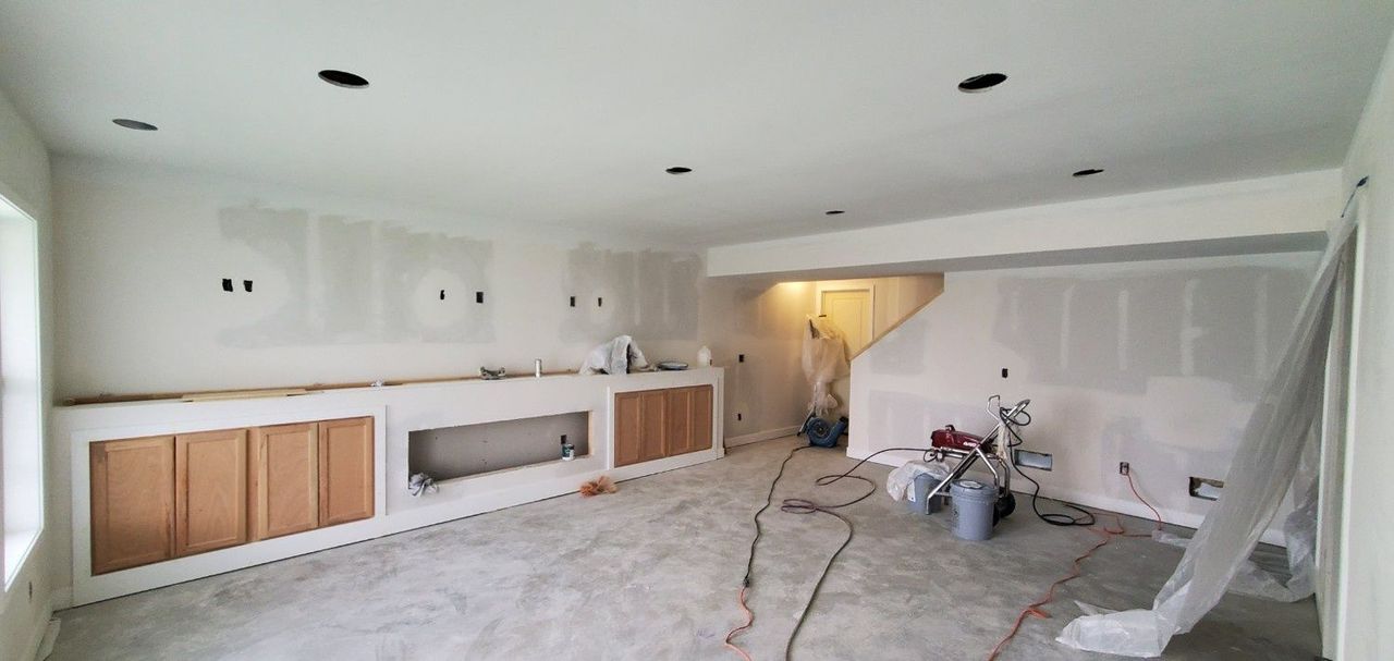 Unfinished living room with white cabinets, exposed floor, and construction materials scattered around.