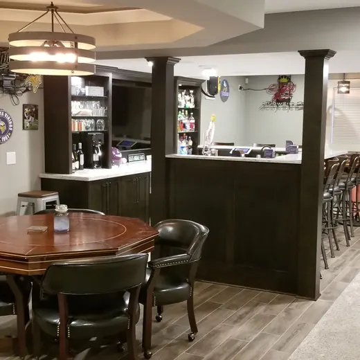 Basement rec room with bar, round table, pool table, and wall art