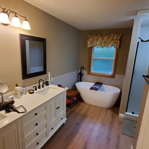 Bathroom with double vanity, large mirror, tub, and shower in warm wood tones
