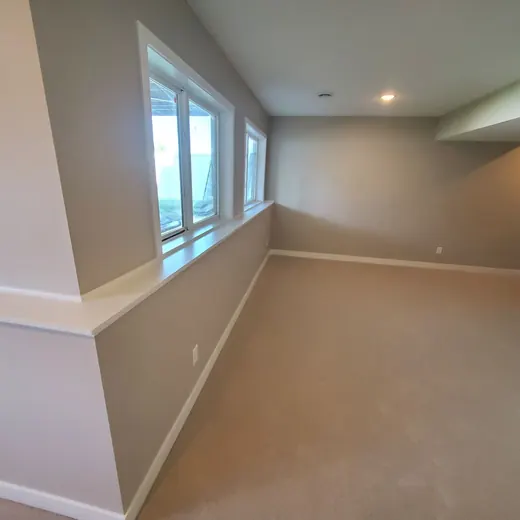 Empty beige room with large windows and recessed ceiling lights