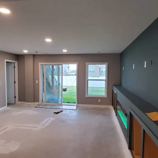 Empty gray living room with carpet, sliding glass doors, and a dark accent wall
