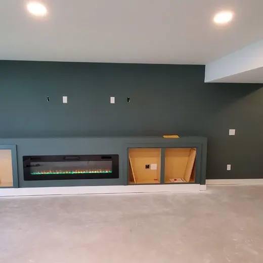 Empty living room with dark accent wall, built-in fireplace, gray carpet, and white ceiling lights