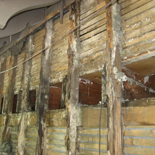 Exposed wall framing with damaged, stripped drywall and insulation in a construction or renovation site