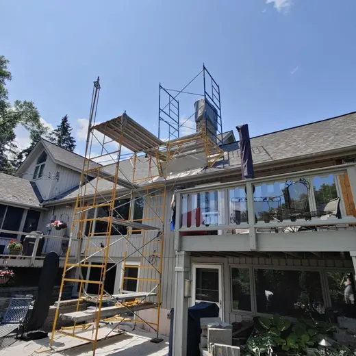 House exterior with scaffolding during roof renovation under a clear blue sky