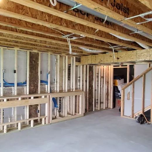 Interior of a house under construction with exposed wooden framing and concrete floor