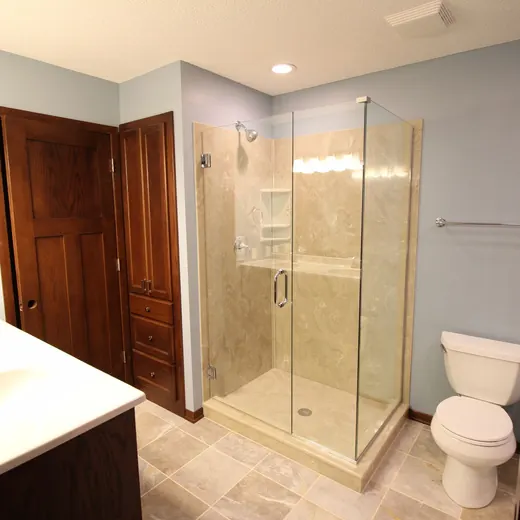 Modern bathroom with glass shower, toilet, double sink, and wood doors