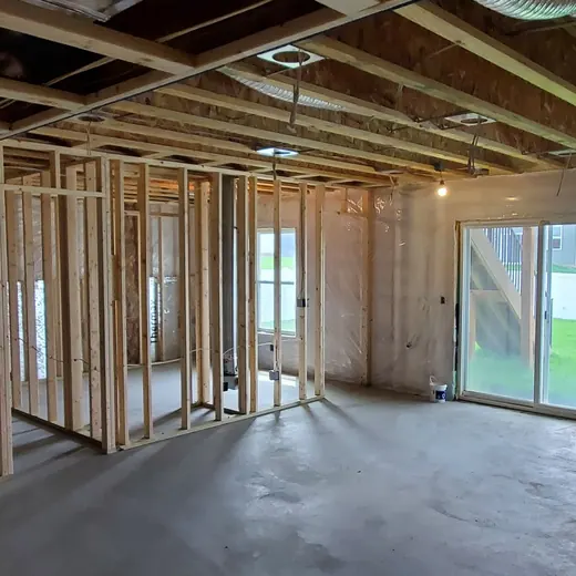 Partially finished basement with exposed studs, concrete floor, and sliding glass door to a backyard.