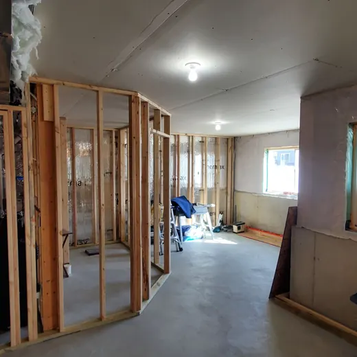 Partially framed interior room under construction with exposed studs, drywall, and debris on the floor