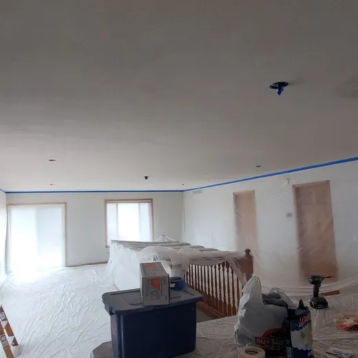 Renovation room with plastic-covered walls, ceiling tape, and construction tools scattered around