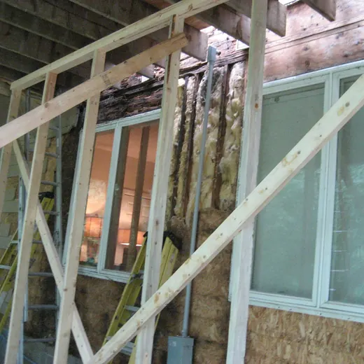 Scaffolded wooden wall with windows and exposed insulation at a building construction site