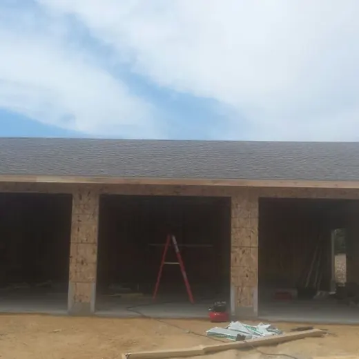 Single-story brick building under construction with a wide front porch and open doorways.