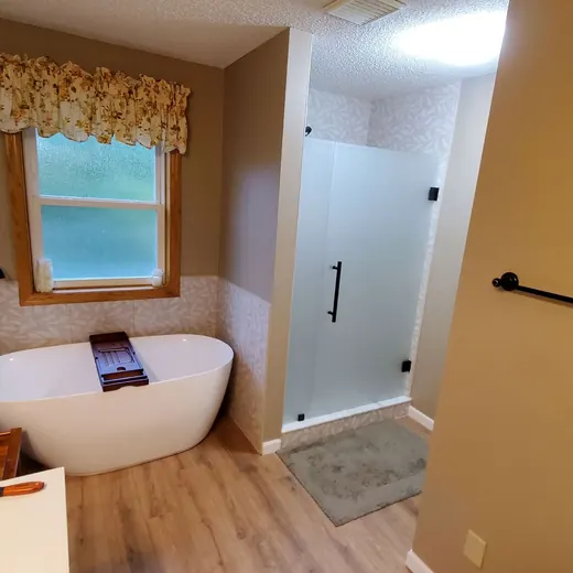 Small bathroom with a freestanding tub, shower, and window with a valance, finished in beige and wood tones